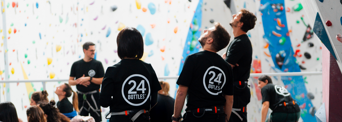 24Bottles Employees wearing climbing gear with '24 Bottles' logo in an indoor climbing gym.